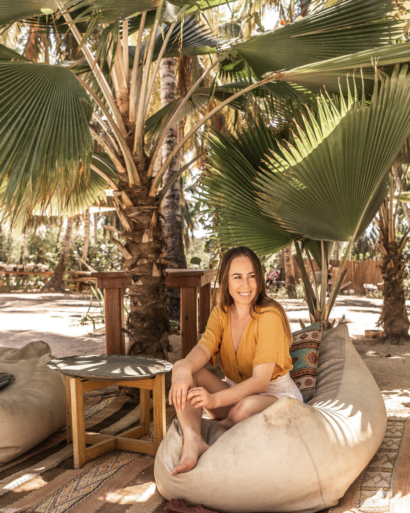 Bohemian floor cushions, rugs, and furniture underneath palm trees on the sand, featured at Eteka Beach Longe & Hotel - Cartagena, Colombia