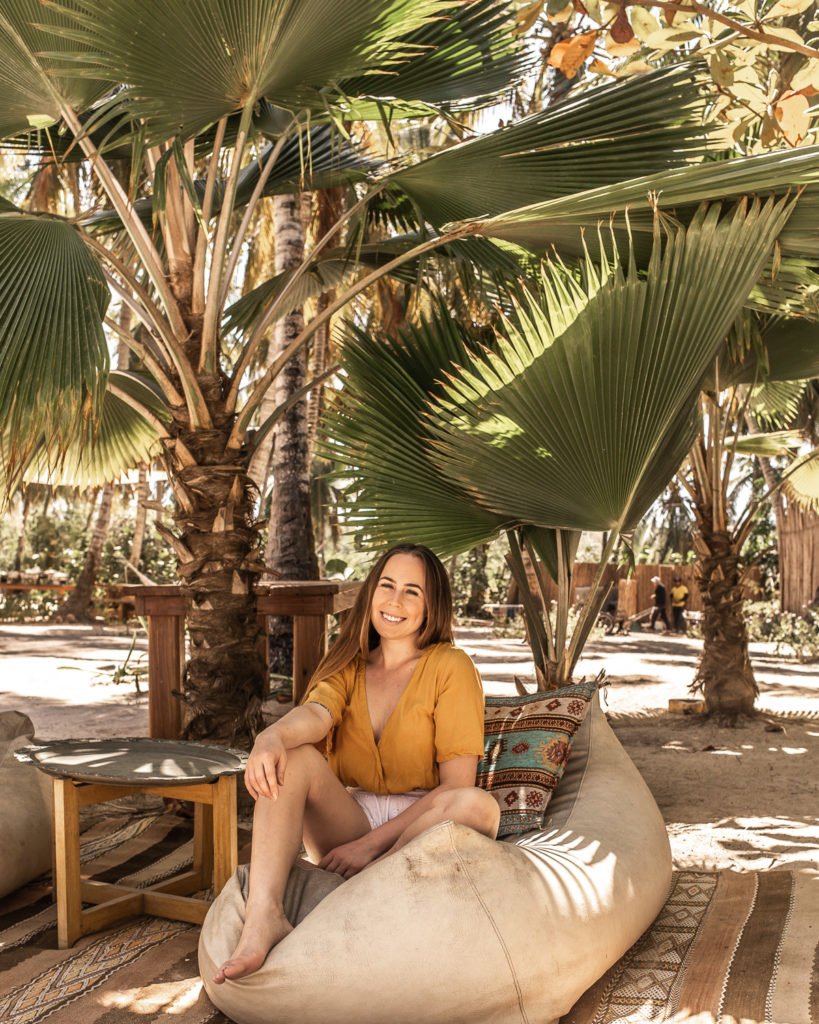 Bohemian floor cushions, rugs, and furniture underneath palm trees on the sand, featured at Eteka Beach Longe & Hotel - Cartagena, Colombia