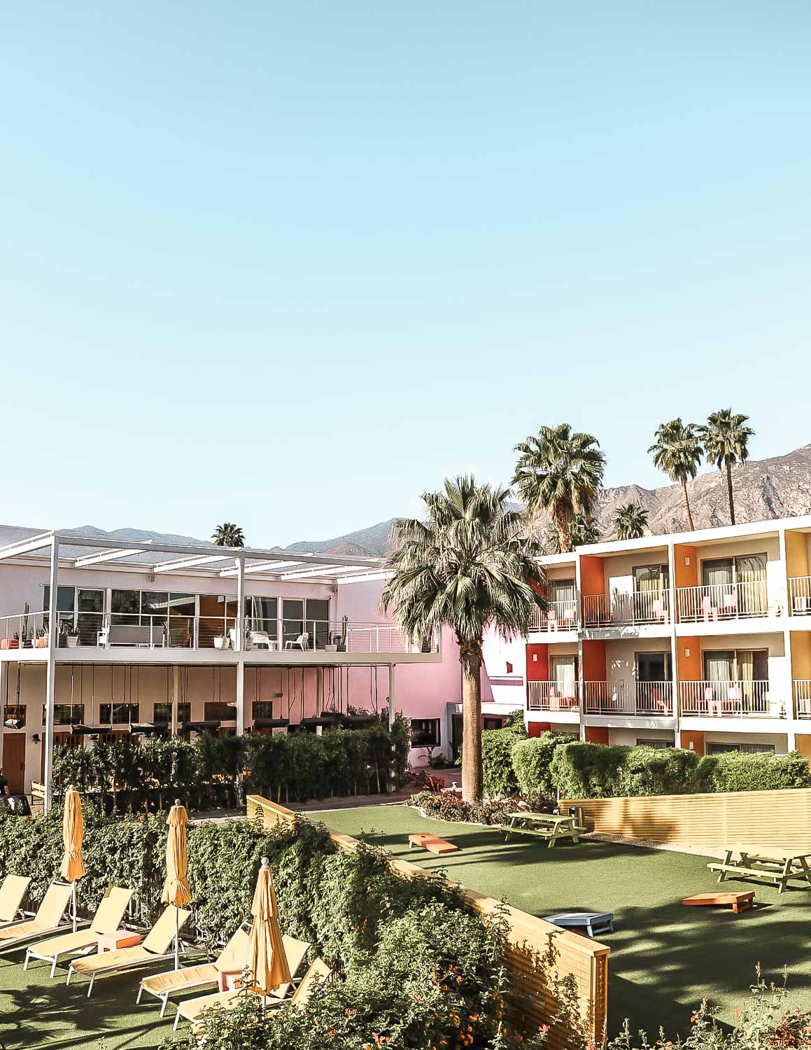 Colorful courtyard featuring lounge chairs and patio games at the Saguaro Hotel in Palm Springs, California.