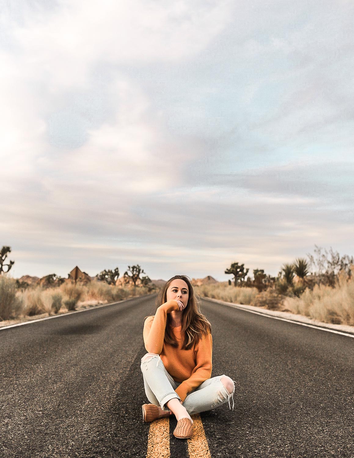 Rylie sitting in the middle of an open road in Joshua Tree, California.