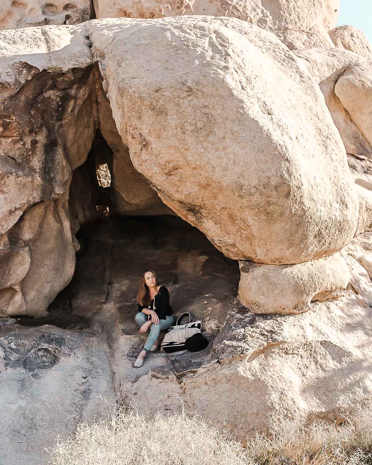 Rylie sitting underneath the rocks in Quail Springs in Joshua Tree National Park.